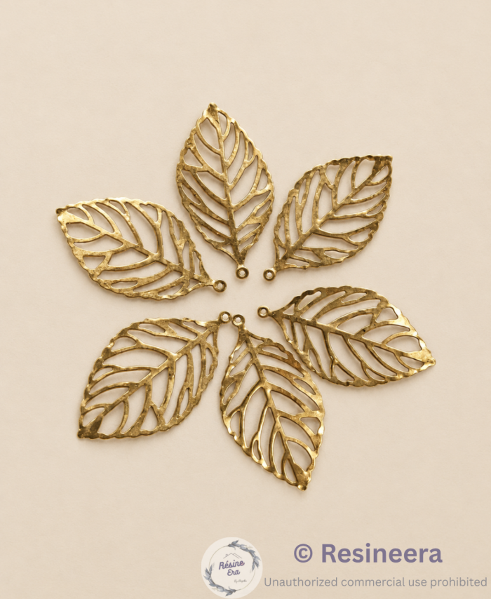 Gold filigree leaf metal charms arranged in a circular pattern on a white background.