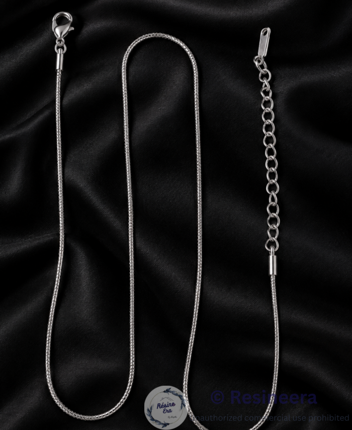 Silver anti-tarnish chain necklace with lobster clasp and extension chain on a beige background.